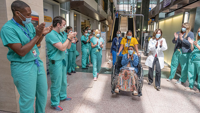 Ochsner Health employees applauding a patient being discharged in a wheel chair.