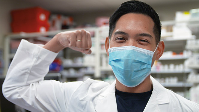 Male Ochsner doctor wearing face mask and flexing bicep
